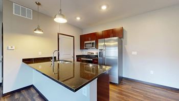 A kitchen with a black granite countertop and stainless steel appliances.